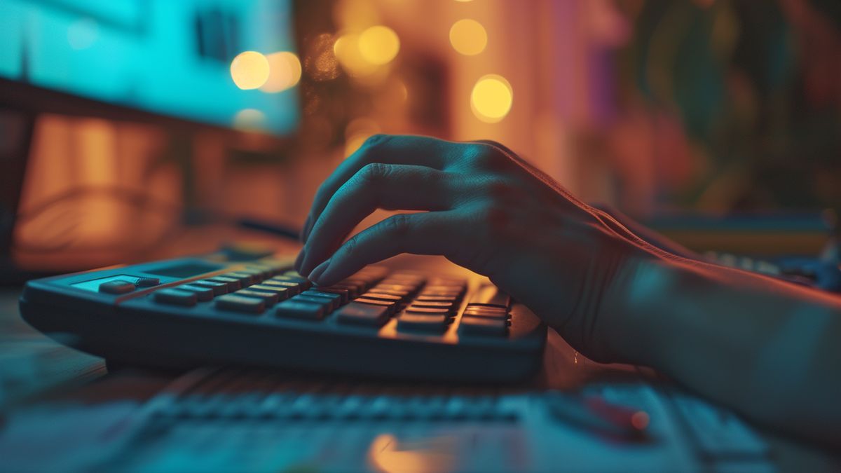 Finger tapping on calculator keys with income and expense records